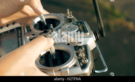 Hands holding a transmitter controlling FPV drone Stock Photo