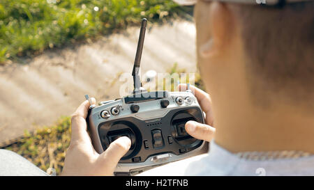 Hands holding a transmitter controlling FPV drone Stock Photo
