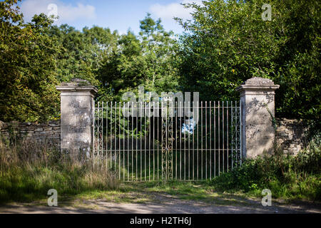Private country estate with locked large iron gates and stone wall on a country lane. Stock Photo