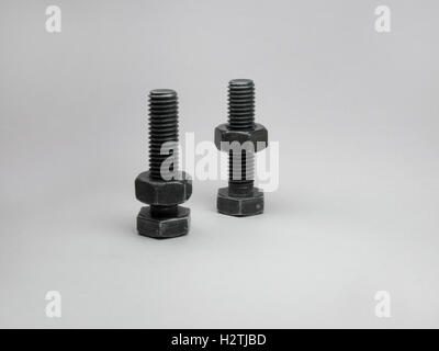 Two connecting bolts in black color, with nuts, screwed on them Stock Photo