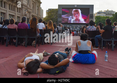 Buenos Aires, Argentina. 13 Jan, 2016. People gather in front of a giant screen during a projection of David Bowie's videos. Stock Photo