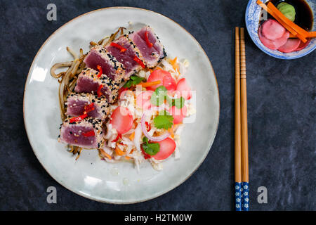 Sesame seeds crusted seared tuna with spicy asian salad and pickled radishes Stock Photo