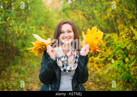 Young woman holding tree leaves in the hands and smiling Stock Photo