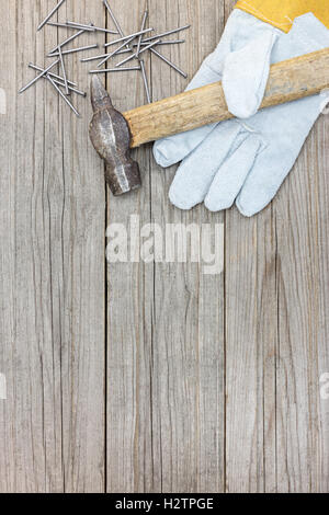 wooden grey background with old hammer, nails and working gloves for house repair and construction Stock Photo
