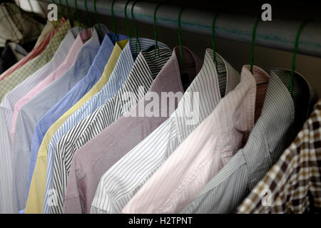 Row of dress shirts hanging on hangers in closet choice of clothing Stock Photo