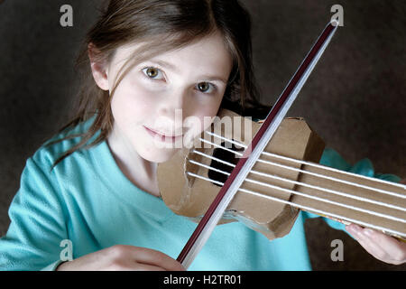 Young girl playing toy violin smiling happy Stock Photo