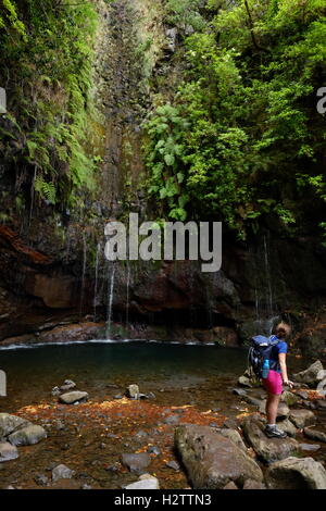 Young female hiker watching the 25 Fontes Falls in the Rabaçal mountains, Madeira, Portugal Stock Photo