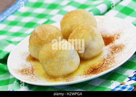 Fruit dumplings sprinkled with sugar and cinnamon on white plate, closeup Stock Photo