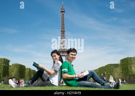 Asian couple student reading book together at outdoors park near Eiffel Tower in Paris, France. Abroad study in Paris, France. Stock Photo