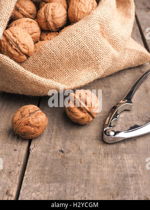 Delicious walnuts in a bag on a wooden table with a nutcracker Stock Photo