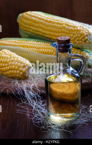 Fresh corn with bottle of oil on wooden background Stock Photo