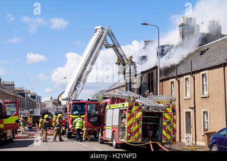 Scottish Fire and Rescue Service firefighters up a ladder fighting a burning building in Elie and Earlsferry, Fife, Scotland, UK Stock Photo