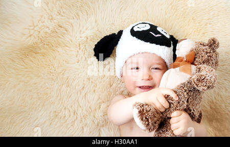 one year old baby lying in sheep hat on lamb wool Stock Photo