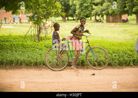 Happy children ride a bicycle in rural Réo Department, Burkina Faso, West Africa. Stock Photo