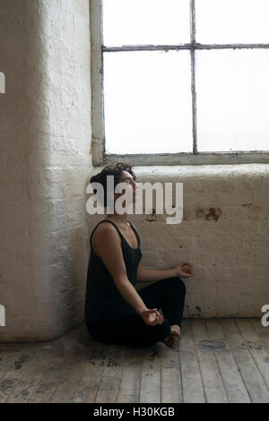 Woman practicing yoga by the window Stock Photo