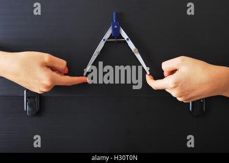 Hands Holding a Technical compass on an old and ruined Black Briefcase Stock Photo