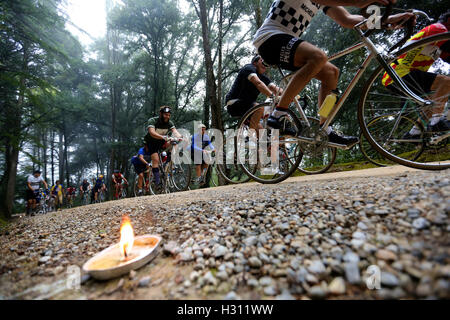 Tuscany, Italy. 2nd Oct, 2016. Cyclists ride past a forest where candles are lit to lighten the gravel road during the 'Eroica' cycling event for old bikes in the Chianti area of Tuscany, Italy, on Oct. 2, 2016. More than 6,000 cyclists from 65 countries and regions, wearing vintage cycling jerseys, riding vintage bicycles built in 1987 or earlier, took part in the 'Eroica' (heroic) cycling event through the Strade Bianche, the gravel roads of the Chianti area of Tuscany. © Jin Yu/Xinhua/Alamy Live News Stock Photo