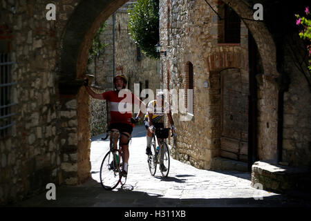 Tuscany, Italy. 2nd Oct, 2016. Two cyclists ride their vintage bikes to past a town during the 'Eroica' cycling event for old bikes in the Chianti area of Tuscany, Italy, on Oct. 2, 2016. More than 6,000 cyclists from 65 countries and regions, wearing vintage cycling jerseys, riding vintage bicycles built in 1987 or earlier, took part in the 'Eroica' (heroic) cycling event through the Strade Bianche, the gravel roads of the Chianti area of Tuscany. © Jin Yu/Xinhua/Alamy Live News Stock Photo