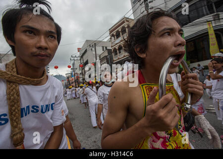 Phuket, Thailand. 3rd Oct, 2016. A devotee from the Chinese Kuan Tae Kun Shrine has his cheek pierced with a metal ring attends a street procession during the yearly Vegetarian Festival, also knows as Nine Emperor Gods Festival in Phuket on October 03, 2016. The Vegetarian Festival described as a colorful event, is held during the ninth lunar month of the Chinese calendar, and celebrate by the Chinese community of Phuket, where the devotees belief that abstinence from all kind of meat will help them obtain good health along their life. Credit:  Guillaume Payen/ZUMA Wire/Alamy Live News Stock Photo