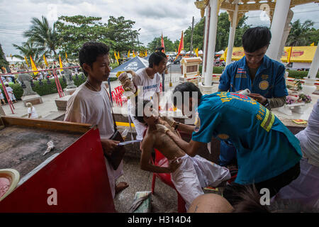 Phuket, Thailand. 3rd Oct, 2016. A devotee from the Chinese Kuan Tae Kun Shrine receive healthcare after being pierced with a metal ring during the yearly Vegetarian Festival, also knows as Nine Emperor Gods Festival in Phuket on October 03, 2016. The Vegetarian Festival described as a colorful event, is held during the ninth lunar month of the Chinese calendar, and celebrate by the Chinese community of Phuket, where the devotees belief that abstinence from all kind of meat will help them obtain good health along their life. Credit:  Guillaume Payen/ZUMA Wire/Alamy Live News Stock Photo