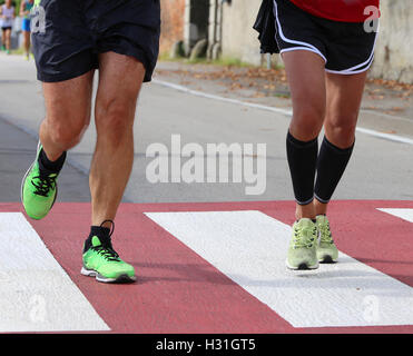two runners during a marathon race in the city on a pedestrian crossing with red and white stripes Stock Photo