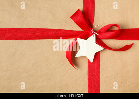 Christmas gift with bow and blank gift tag. Simple recycled wrapping paper and natural jute ribbon. Stock Photo