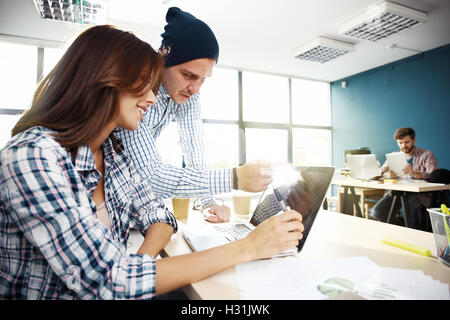 Coworking process, designers team working modern office.Photo young creative manager showing new startup idea monitor. Desktop computers on wood table. Blurred background, film effect. Stock Photo