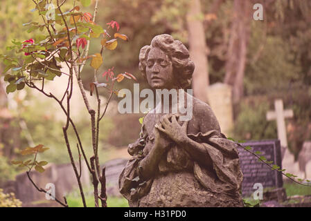 Gravestone tombstone statue of a woman in deep sorrow at Highgate Cemetery East in London, England. Stock Photo