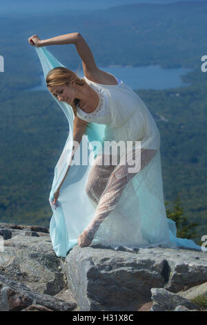 Female dancer in white dress dancing with green fabric in the wind on summit of Mt. Kearsarge, New Hampshire. Stock Photo