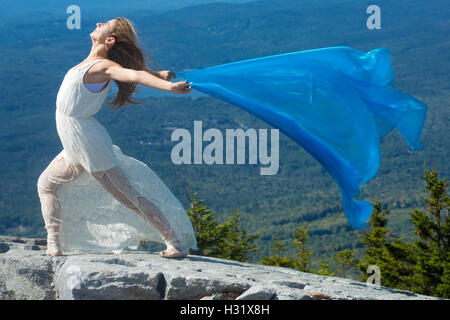Female dancer in white dress dancing with blue fabric in the wind on summit of Mt. Kearsarge, New Hampshire. Stock Photo