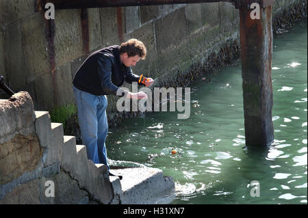 Man fishing in harbor with hand line. Stock Photo