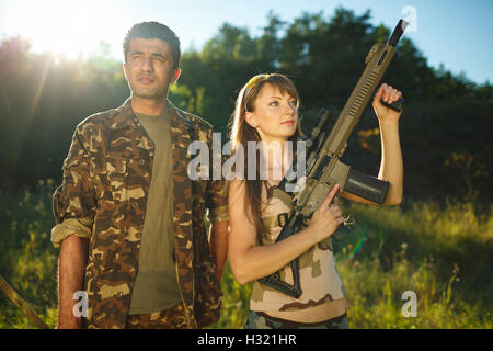 White young girl and an Arab man in camouflage with a weapon in the hands of outdoors Stock Photo