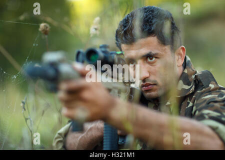 Man of Arab nationality in camouflage with a gun for trap shooting aiming at a target Stock Photo