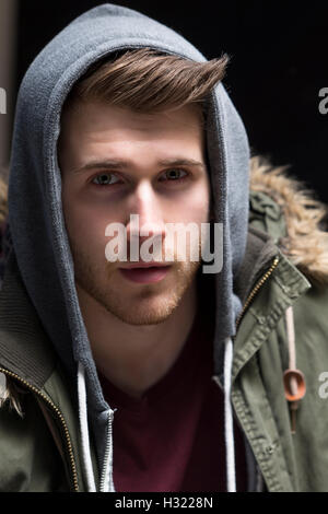 Close up portrait of a young man posing with his hood up. Stock Photo