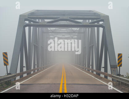 Photo looking down the road on a fog covered bridge. Stock Photo