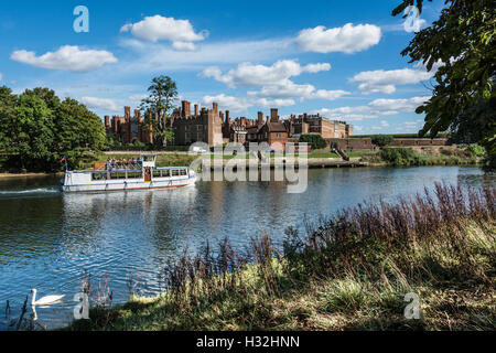 A pleasure cruiser passing Hampton Court Palace, Surrey, England, UK Stock Photo