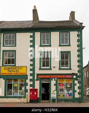 Old post office and adjacent shop, three stories high, painted green and cream, in main street of English town of Egremont Stock Photo