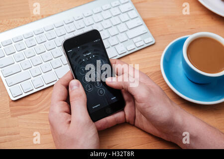 Hands holding smartphone with access identification password on the screen over wooden table Stock Photo