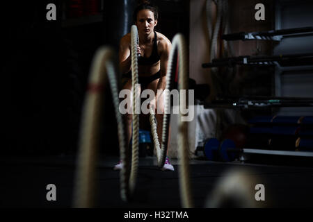 Battle ropes exercises. Young and strong man doing CrossFit exercises ...