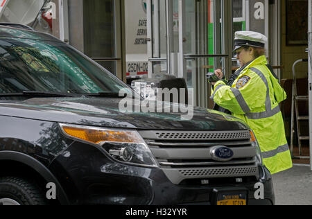 A New York City Police department traffic agent using a portable electronic ticket issuing machine on Bleeker St. in Manhattan Stock Photo