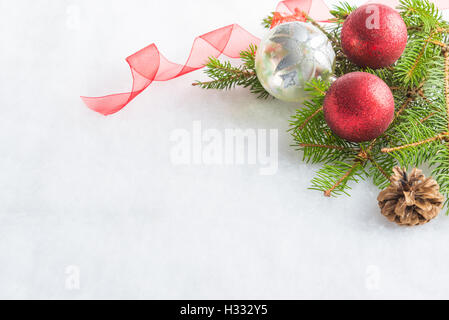 Close up of christmas red and crystal glitter balls, pine and cone over white fluffy background. Christmas decoration. Stock Photo