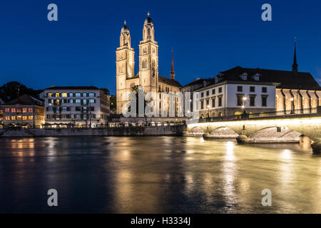 A night view of the Zurich Cathedral (Grossmunster) with its lights reflecting on the Limmat river in Zurich, Switzerland larges Stock Photo