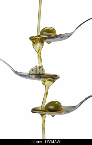 Olive oil poured into a spoon and falling from one to another spoon Stock Photo