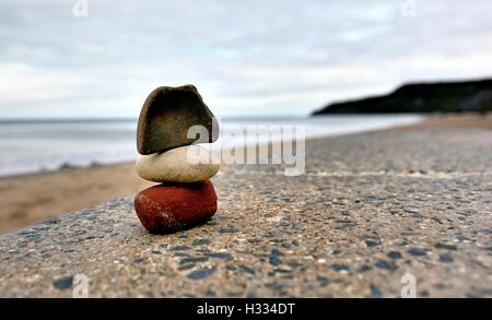 3 Pebbles stacked on a coastline wall in Cayton Bay North Yorkshire England UK Stock Photo