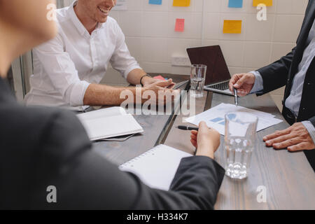 Close up of businessman explaining a financial plan to colleagues at meeting. Business people discussing a financial plan around Stock Photo