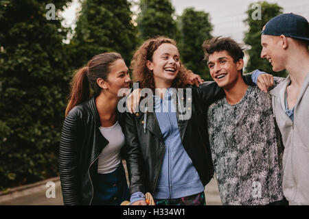 Portrait of four young friends together smiling. Mixed race group of people having fun outdoors. Stock Photo