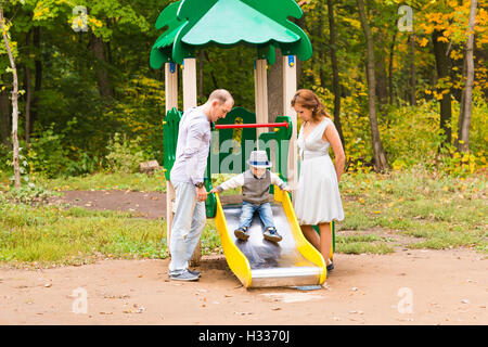Happy parents with son playing at children's slide. Stock Photo