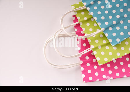 Three paper bags to buy colored with white circles stacked in a row on white table. Top view Stock Photo