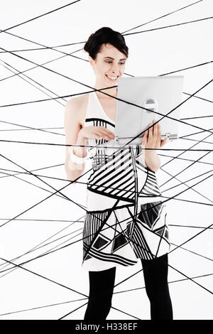 Woman, 24, dressed in the style of the 60s, standing between spanned threads, symbolic image network Stock Photo