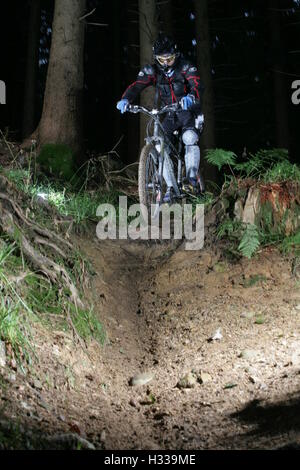 Downhill mountain biker riding on a trail through a forest Stock Photo